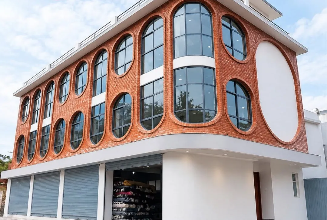 Three-storey red-brick commercial building in Sorhakhutte with rows of arched black aluminium windows